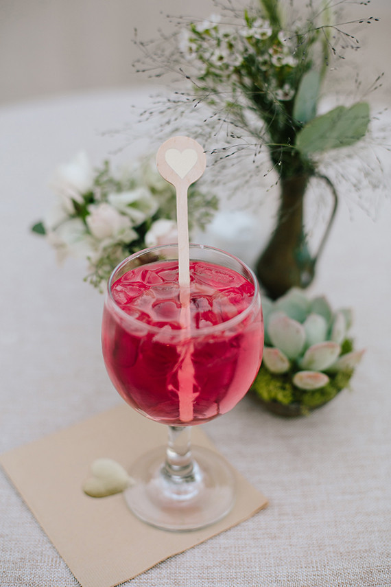 Red cocktail with wooden heart cocktail stirrer