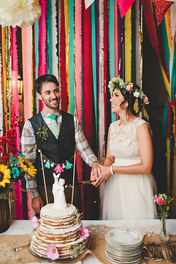 Couple at wedding cake table with cake topper