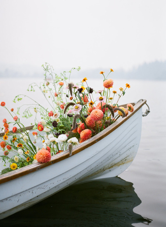End of summer retro engagement shoot in a rowboat full of flowers