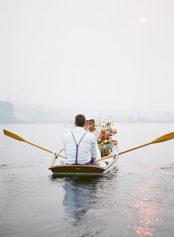 End of summer retro engagement shoot in a rowboat full of flowers