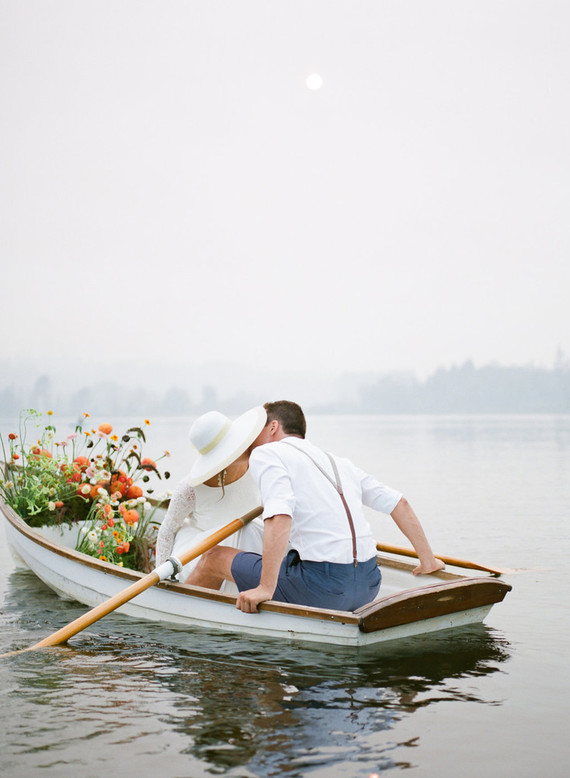 End of summer retro engagement shoot in a rowboat full of flowers