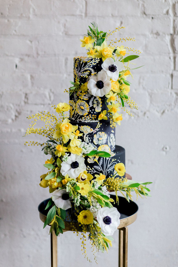 black wedding cake with anenomes and yellow flowers