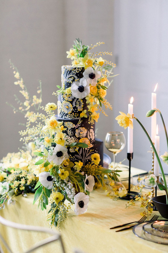 black wedding cake with anenomes and yellow flowers