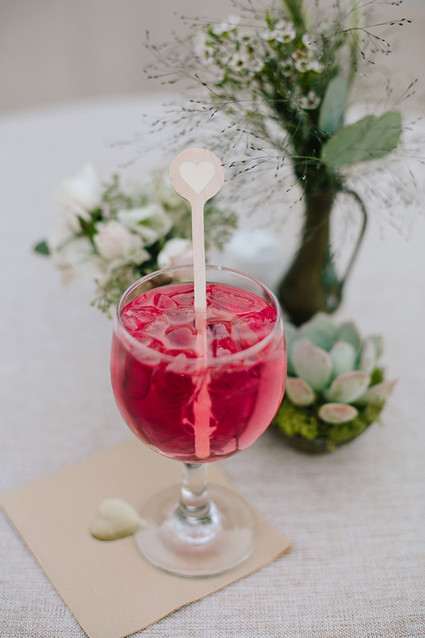 Red cocktail with wooden heart cocktail stirrer