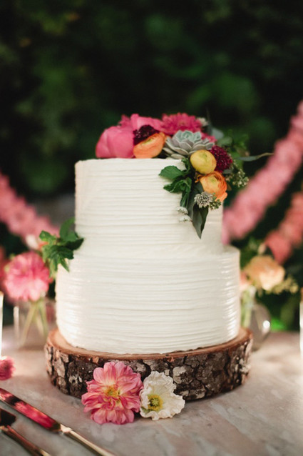 White cake with wood base and colorful flowers