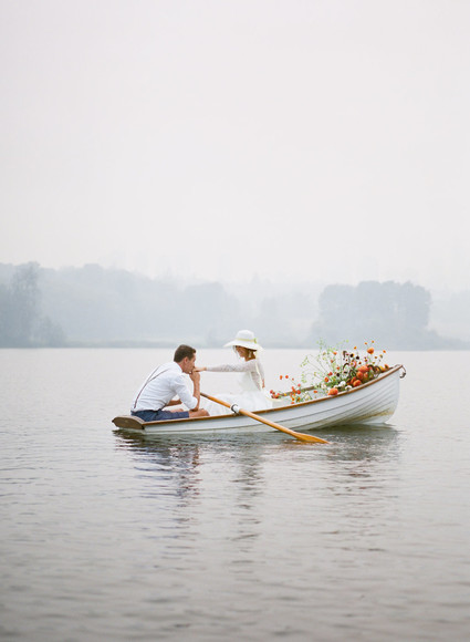 End of summer retro engagement shoot in a rowboat full of flowers